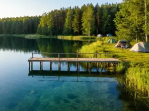 Camp Mazury nad jeziorem z pomostem i miejscami kempingowymi wśród zielonych lasów