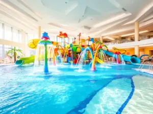Hotel z basenem dla dzieci z kolorowymi zjeżdżalniami i brodzikiem w nowoczesnym wnętrzu aquaparku