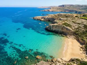 Malta plaże - widok z lotu ptaka na turkusową zatokę z piaszczystym brzegiem i skalistymi klifami