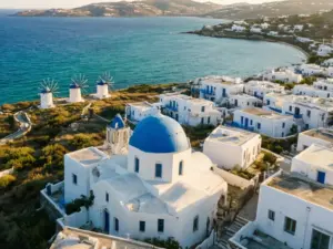 Mykonos wakacje - widok na białe domki z niebieskimi kopułami i wiatraki nad morzem Egejskim