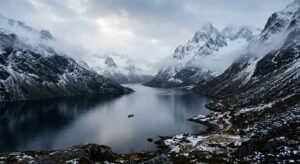 A breathtaking, professional editorial photograph of a deep, misty fjord in northern Norway, surroun
