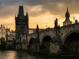 Most Karola w Pradze rozciągający się nad Wełtawą o złotej godzinie z widocznymi gotyckimi wieżami i barokowymi posągami