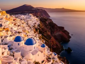 Santorini Grecja - białe domy z niebieskimi kopułami na tle kaldery wulkanicznej i Morza Egejskiego