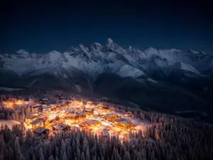 Sylwester w górach - ośnieżone szczyty górskie nocą z lampkami kurortów w dolinie, widok na Tatry zimą