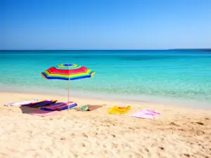 Plaża z parasolem i ręcznikami symbolizująca wakacje letnie - za ile miesięcy są wakacje w Polsce